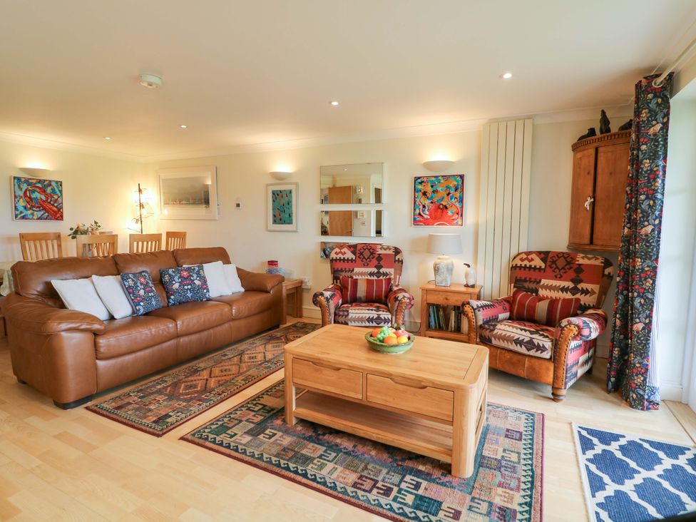A living room with a sofa, armchairs, and a coffee table at 5 Thurlestone Beach Thurlestone