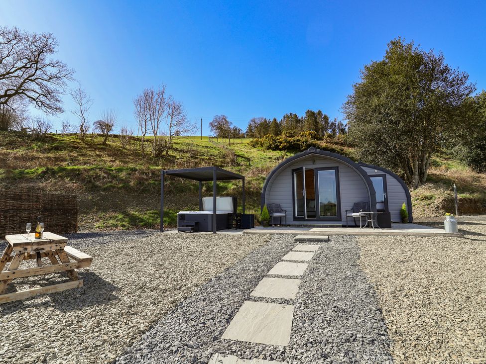 An outdoor area with a cabin, hot tub, and picnic table at Lili Wen Fach Ruthin