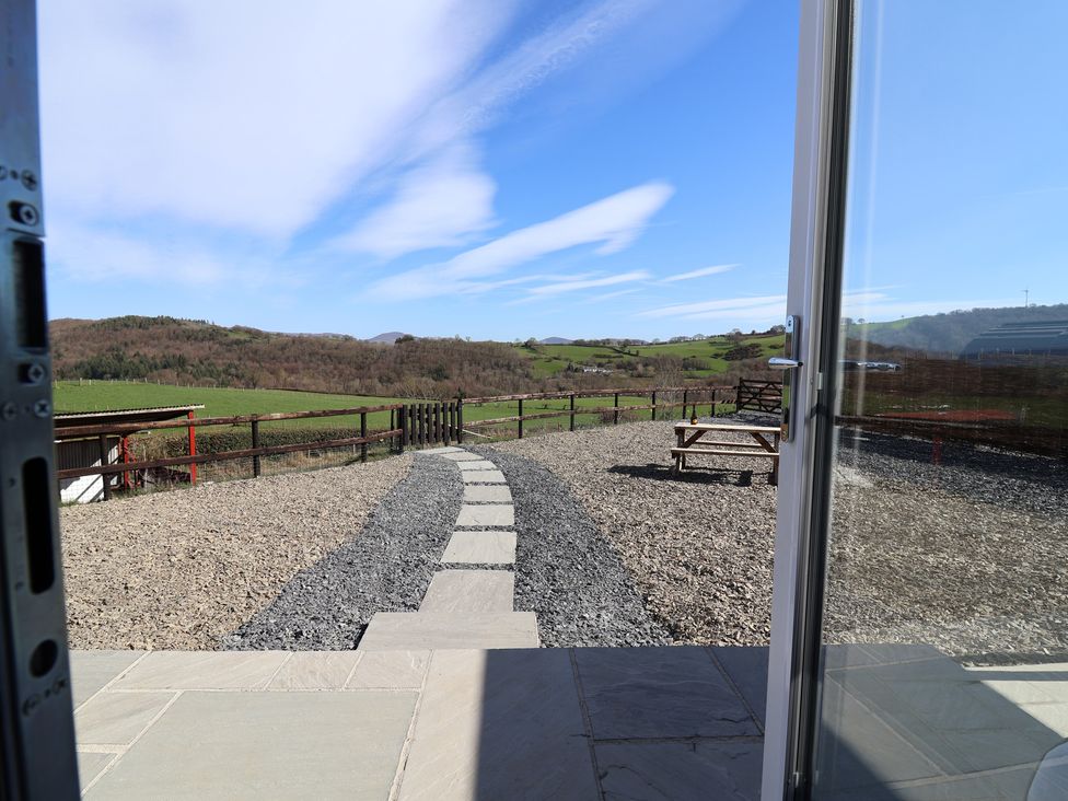 An outdoor area with a gravel pathway and a bench at Lili Wen Fach in Ruthin