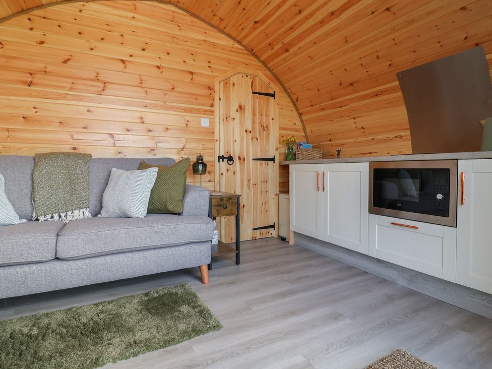 A living room with a sofa and kitchen cabinet at Lili Wen Fach in Ruthin