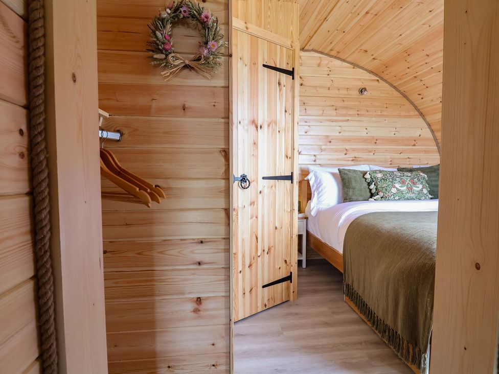 A bedroom with a wooden bed and door at Lili Wen Fach in Ruthin
