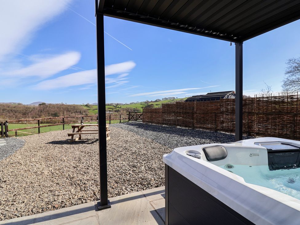 An outdoor area with a hot tub and picnic table at Lili Wen Fach in Ruthin