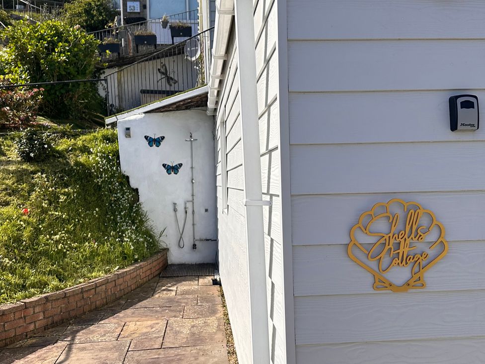 An exterior side view of a building with a sign at Shells Cottage in Looe