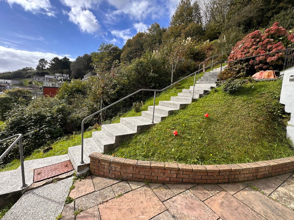 A pathway with stairs and flower bushes at Shells Cottage Looe