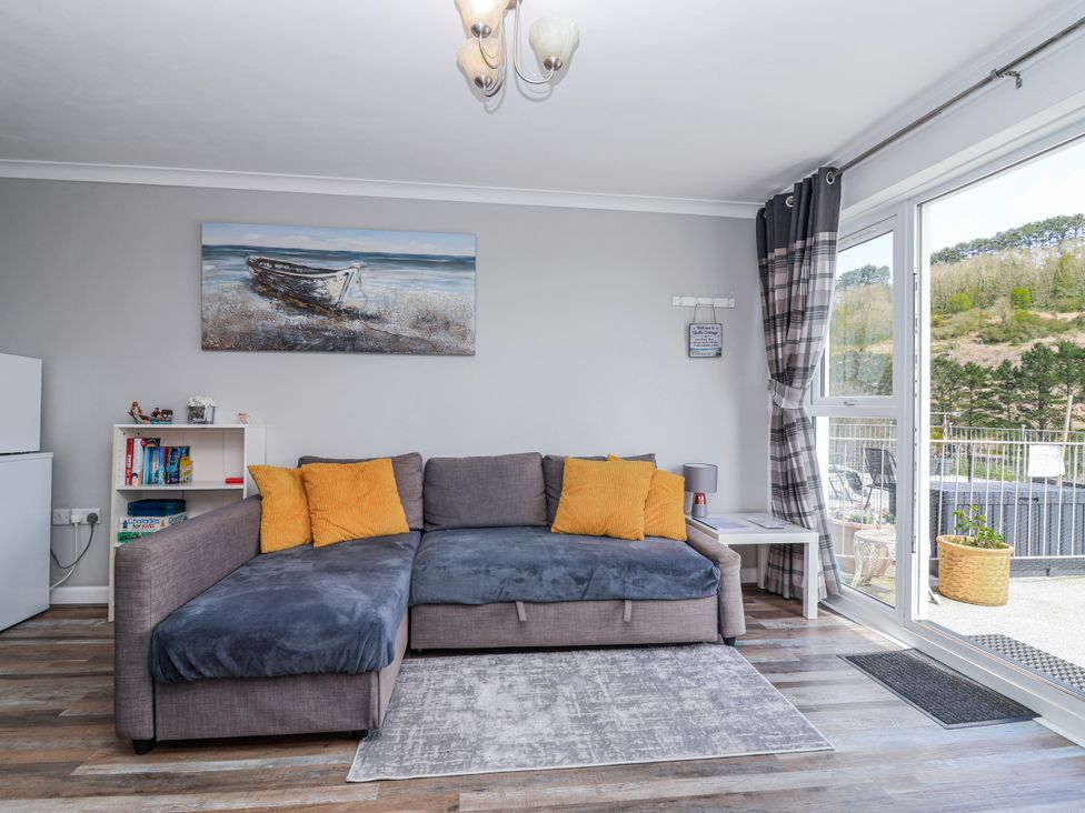 A living room with a sofa and shelves at Shells Cottage in Looe