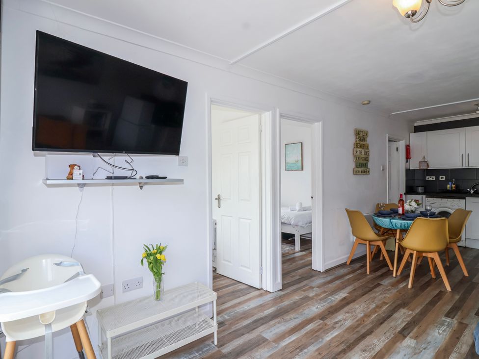 A kitchen with a dining area and a television at Shells Cottage in Looe