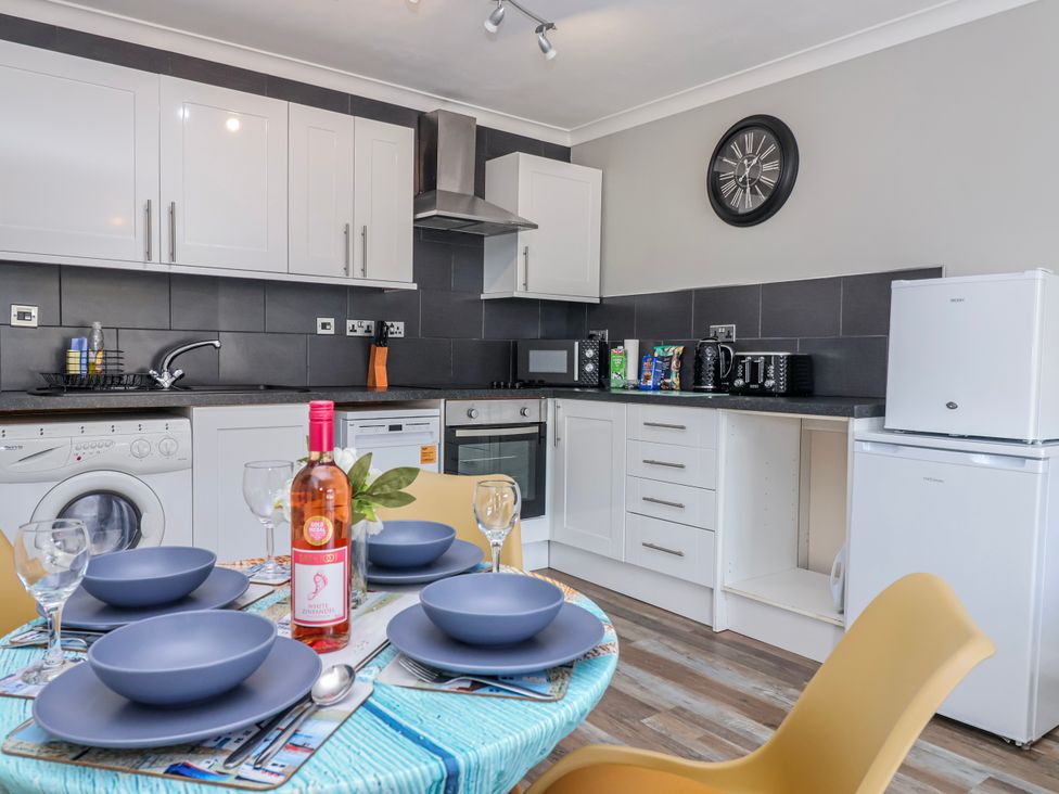 A kitchen with a table set for dinner at Shells Cottage in Looe