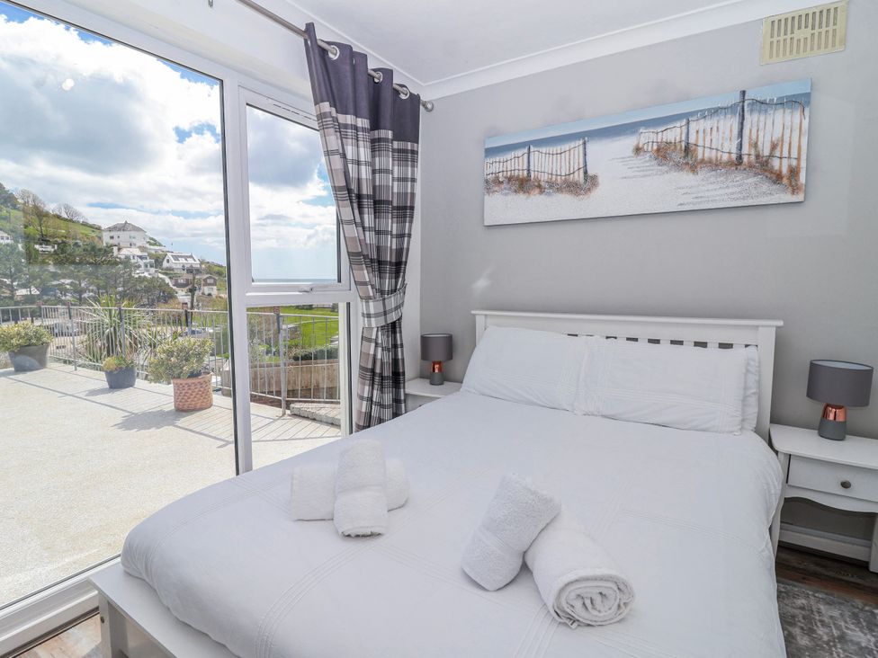 A bedroom with a bed and large windows at Shells Cottage in Looe