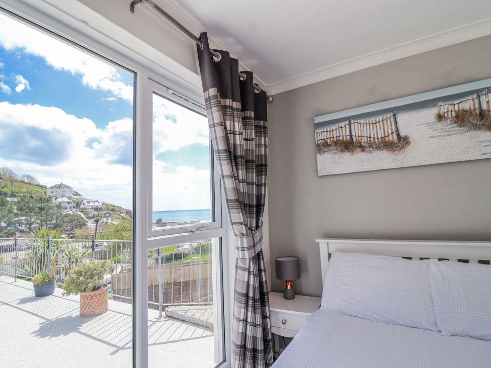 A bedroom with a bed and window view at Shells Cottage in Looe