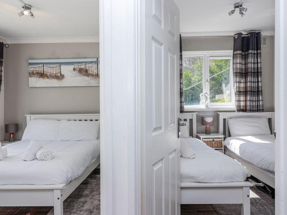 A bedroom with two beds and a window at Shells Cottage in Looe