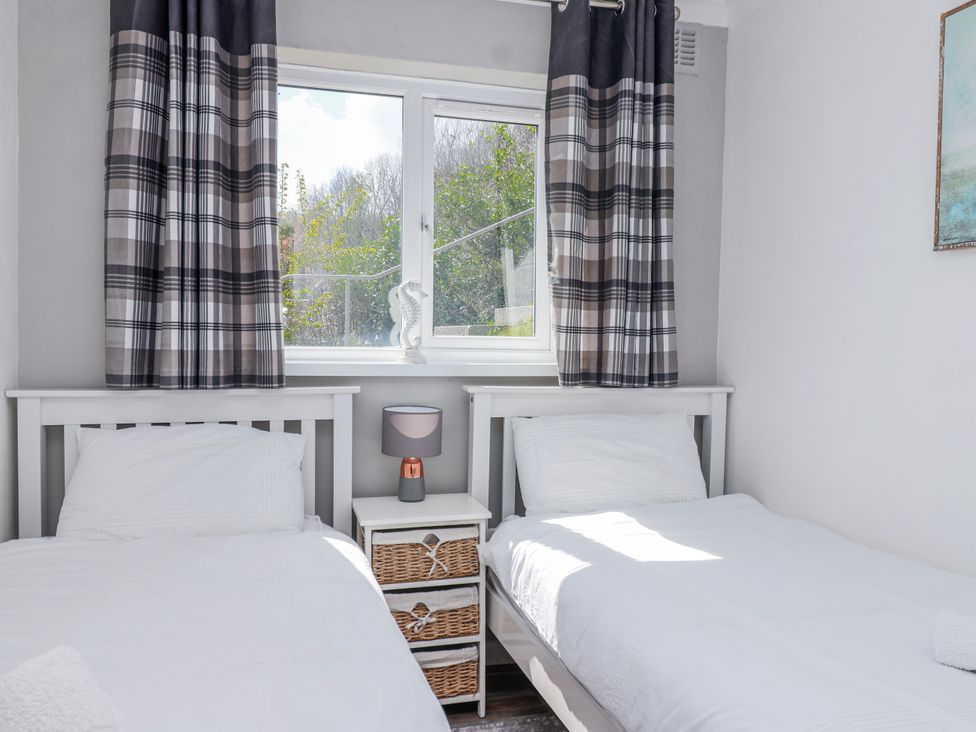 A bedroom with twin beds and a lamp at Shells Cottage in Looe