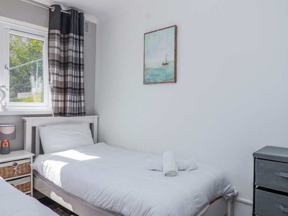 A bedroom with two beds and a window at Shells Cottage in Looe
