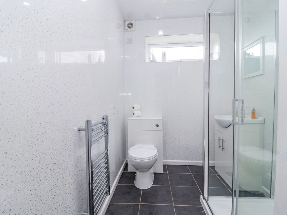 A bathroom featuring a shower, toilet, and sink at Shells Cottage in Looe