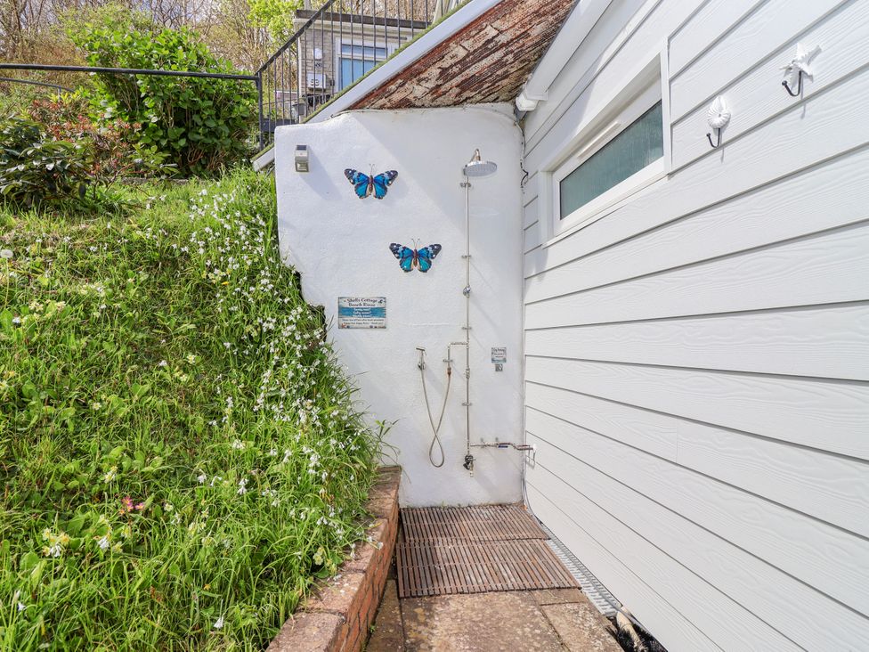 An outdoor area with a shower and decorative butterflies at Shells Cottage in Looe