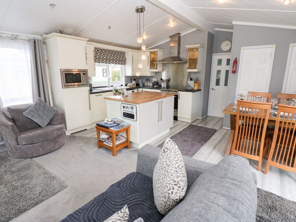 A living room and kitchen area with dining table at A and C Lodge-Plot 21 Armathwaite