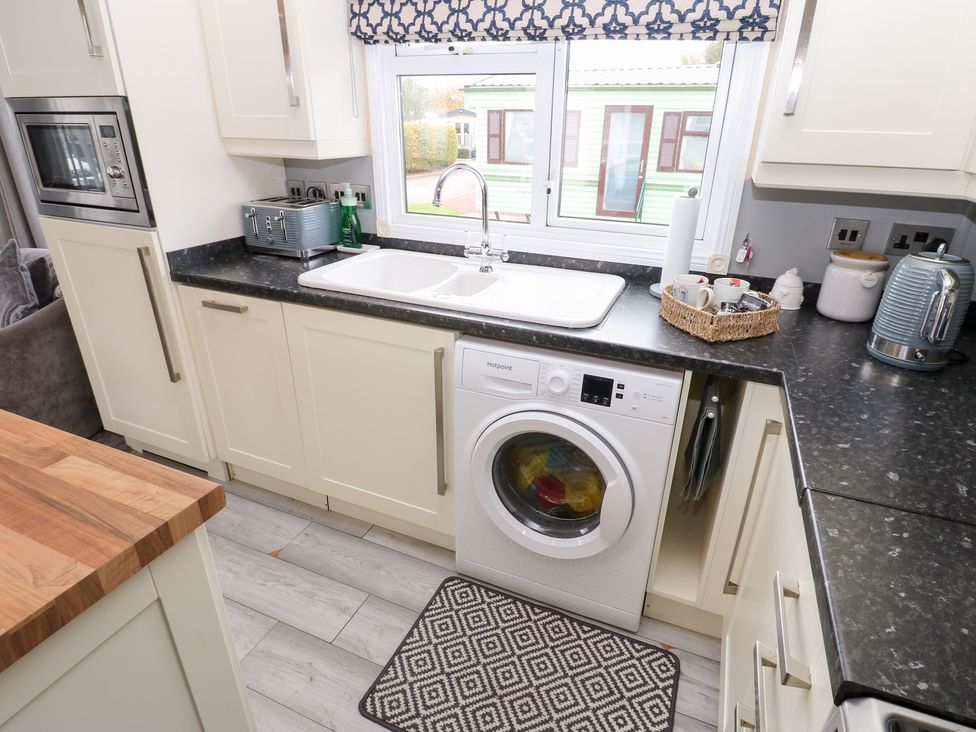 A kitchen with a washing machine and sink at A and C Lodge-Plot 21 Armathwaite