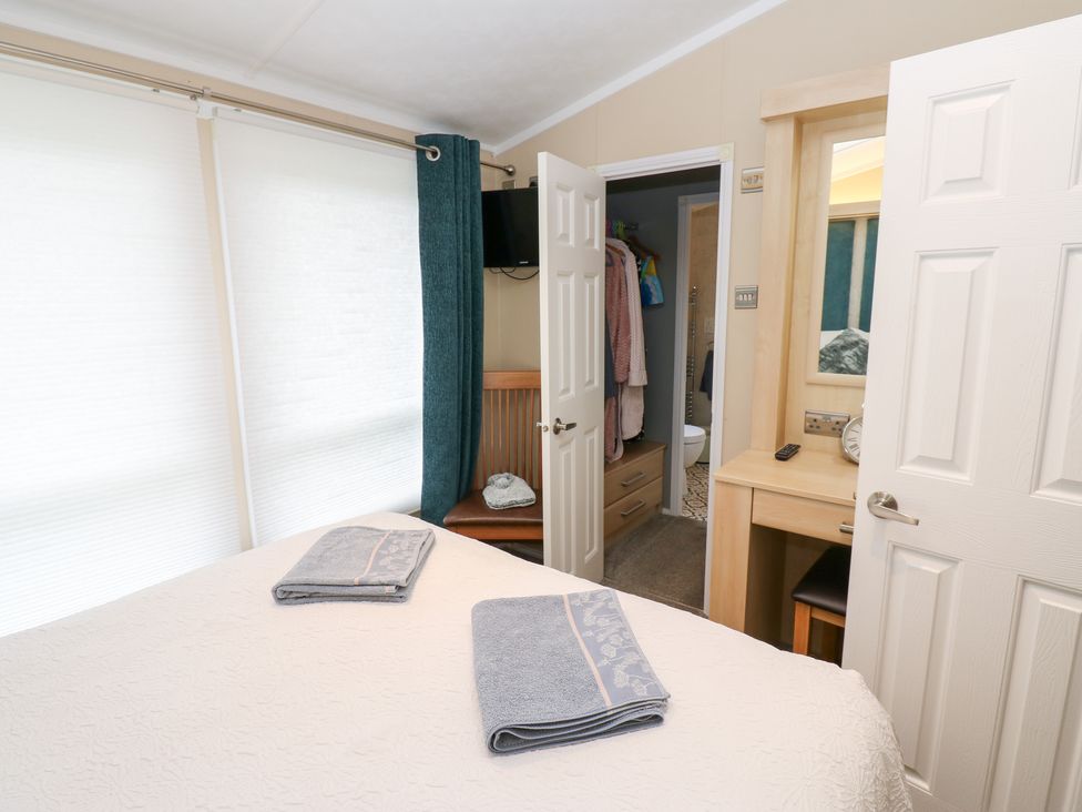 A bedroom with towels on the bed and a door leading to the bathroom at A and C Lodge-Plot 21 Armathwaite