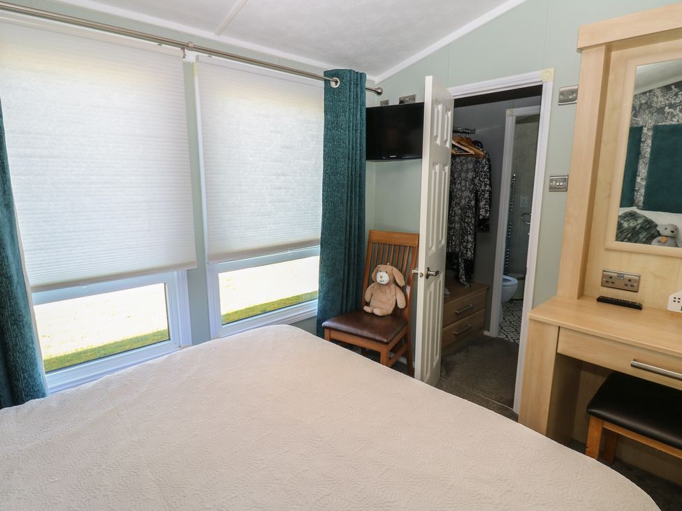A bedroom with a bed, chair, and television at A and C Lodge-Plot 21 Armathwaite