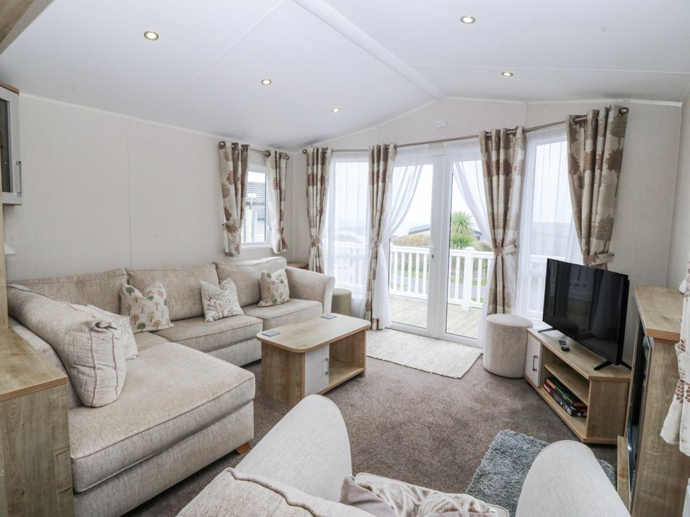 A living room with a sofa and television at Seaviews in Nefyn