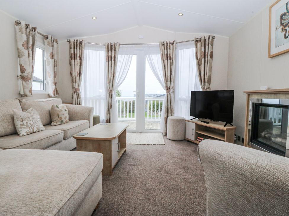 A living room with a sofa and television at Seaviews in Nefyn
