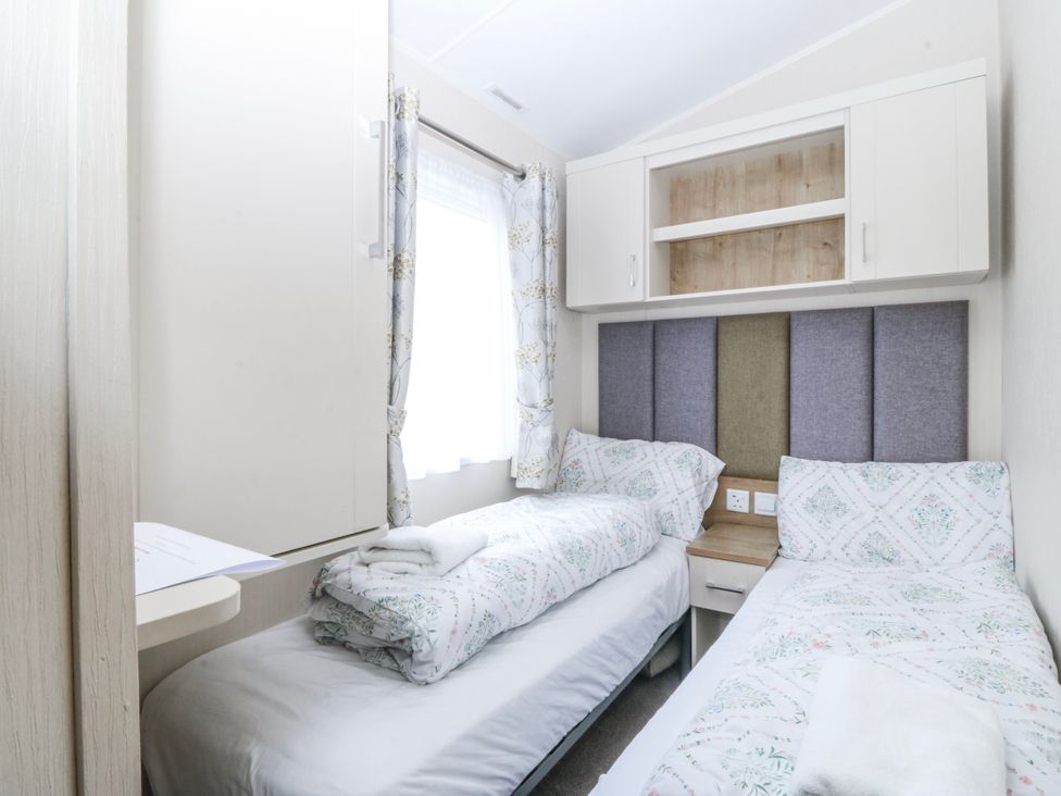 A bedroom with two beds and a wardrobe at Seaviews in Nefyn