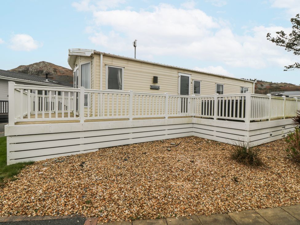 A caravan with decking and gravel outside at Seaviews Nefyn