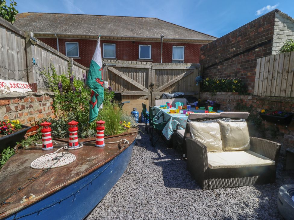 A garden with a boat, table, and chairs at Yr Angor (The Anchor) Llandudno Junction