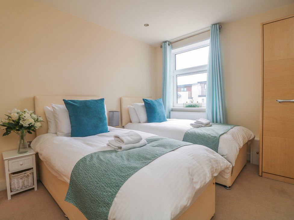 A bedroom with two single beds and a window at Whitewater Seaview in Newquay