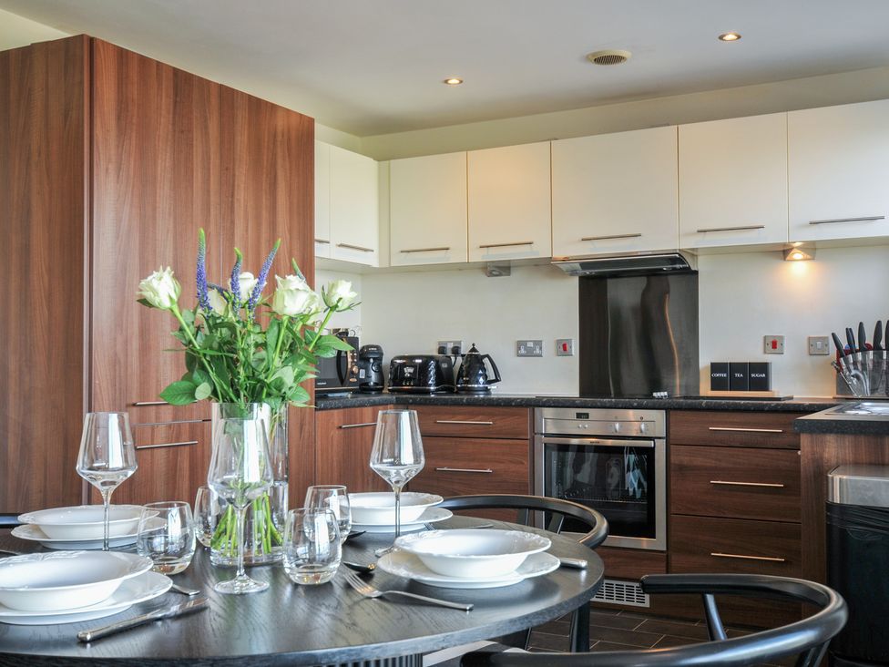A kitchen with a dining table set and flowers at Whitewater Seaview in Newquay