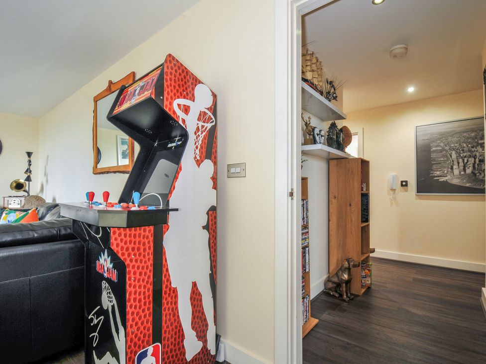 A living room with an arcade machine and shelf at Whitewater Seaview in Newquay