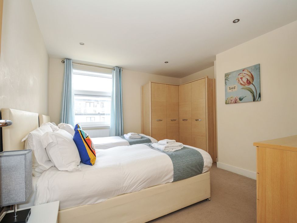A bedroom with two beds and a wardrobe at Whitewater Seaview in Newquay