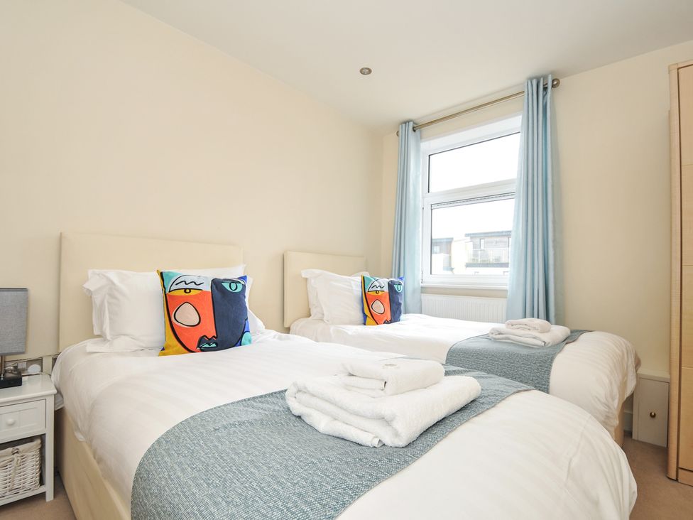 A bedroom with two beds, a lamp, and a window at Whitewater Seaview in Newquay