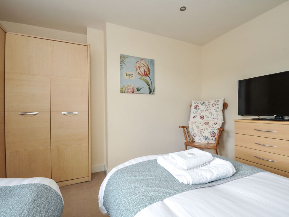 A bedroom with a wardrobe and armchair at Whitewater Seaview in Newquay