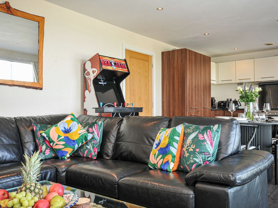 A living room with a sofa and arcade machine at Whitewater Seaview in Newquay