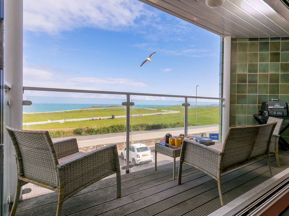 A balcony with chairs and a table overlooking the sea at Whitewater Seaview in Newquay