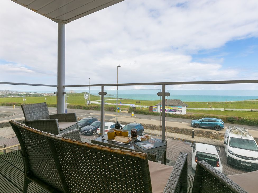 A balcony with a table and chairs overlooking the ocean at Whitewater Seaview in Newquay