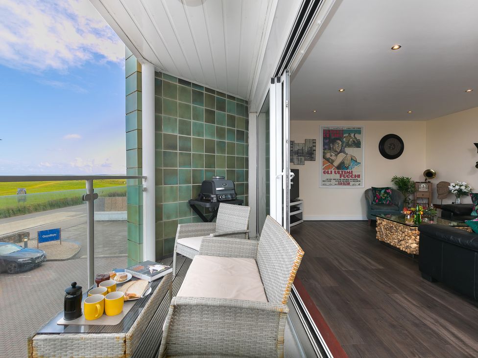 A balcony with chairs and table overlooking grass at Whitewater Seaview in Newquay