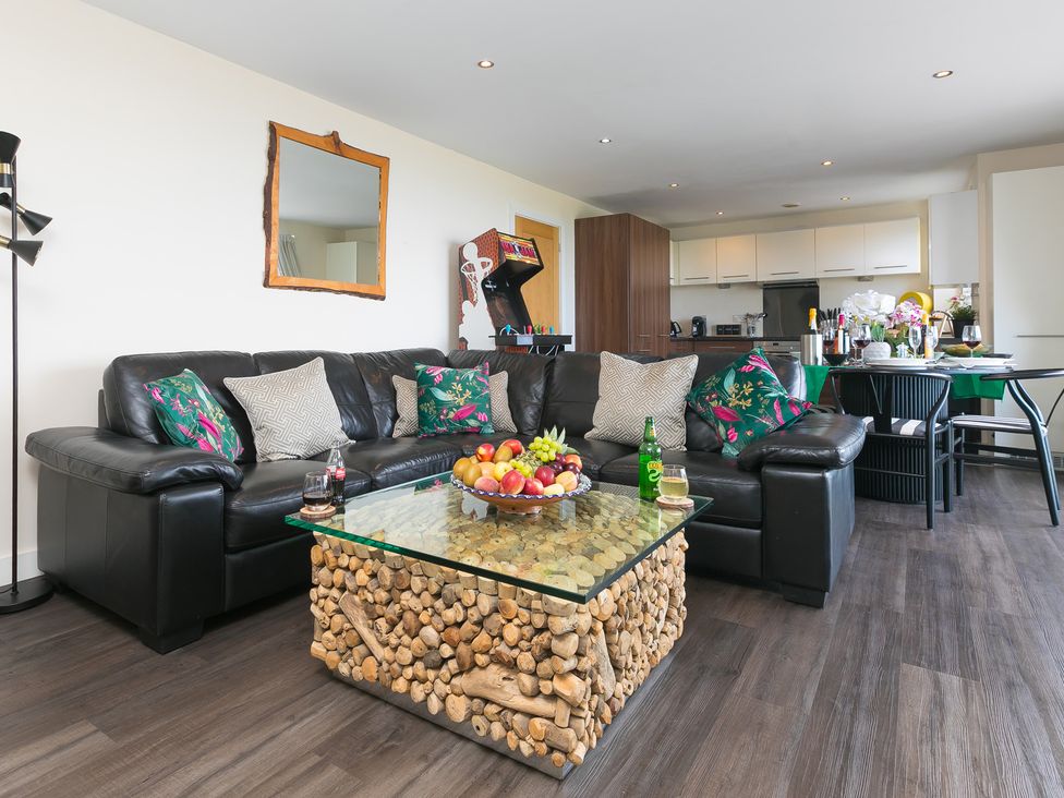 A living room with a black sofa and a coffee table at Whitewater Seaview in Newquay