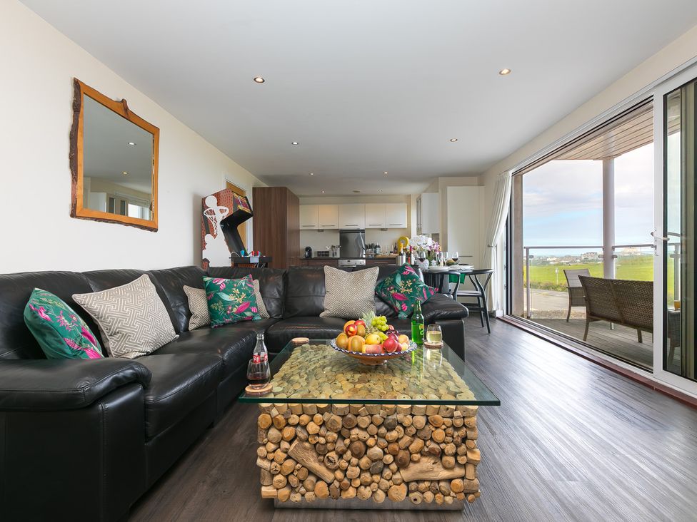 A living room with a coffee table and kitchen area at Whitewater Seaview in Newquay