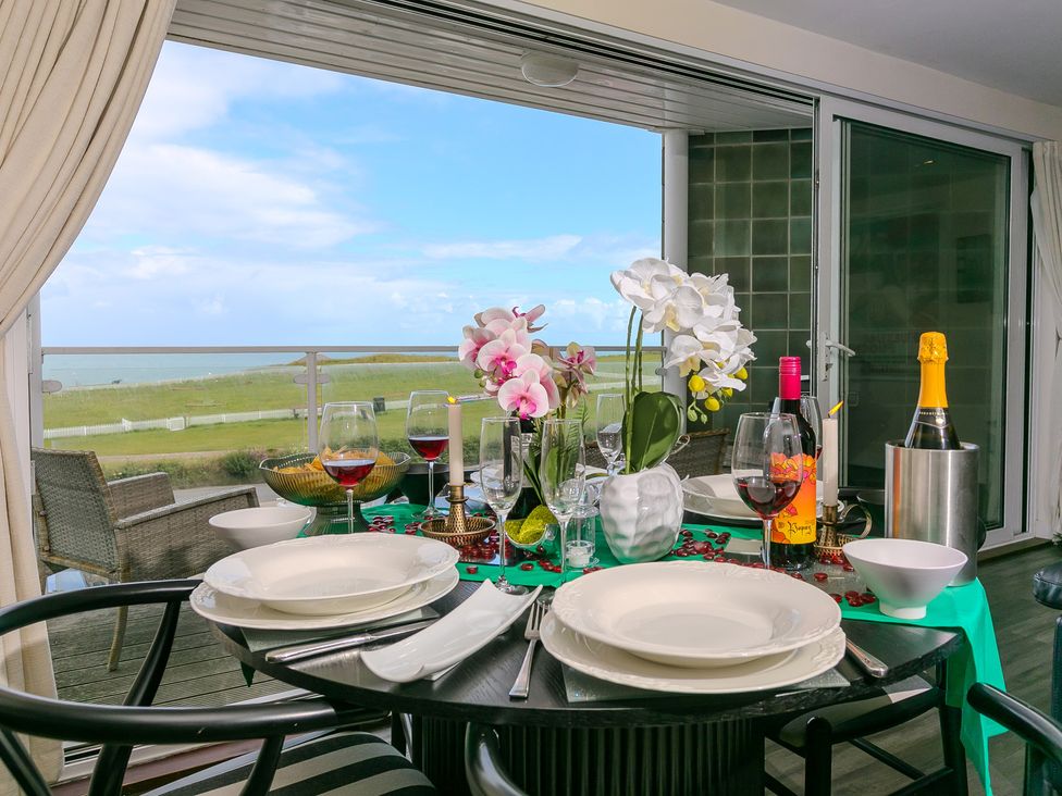 A dining room table set with plates and wine glasses at Whitewater Seaview in Newquay