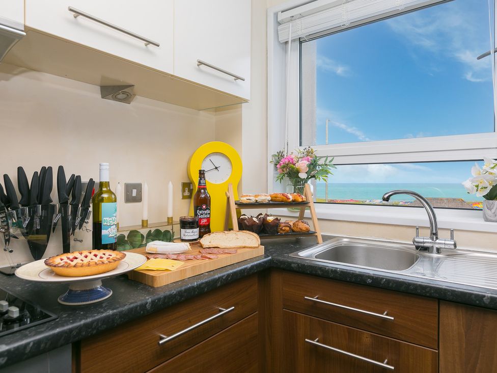 A kitchen with a sink and countertop featuring food and drinks at Whitewater Seaview in Newquay