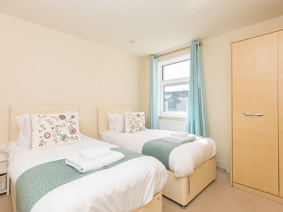 A bedroom with two beds and a wardrobe at Whitewater Seaview in Newquay