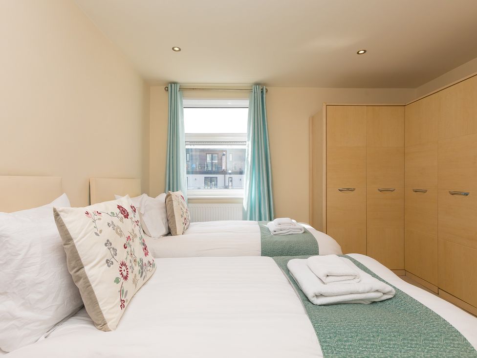 A bedroom with two beds and a wardrobe at Whitewater Seaview in Newquay