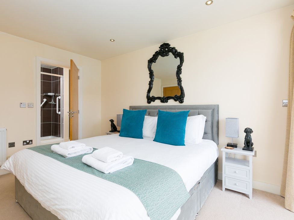 A bedroom with a bed, towels on the bed, and a shower door at Whitewater Seaview in Newquay