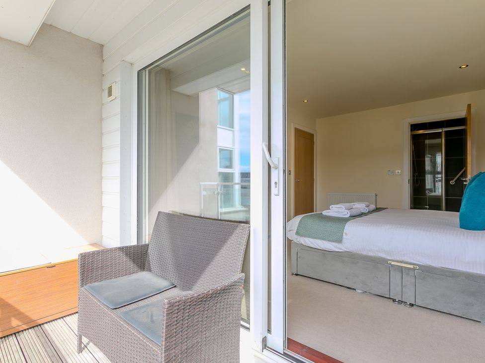 A bedroom with a bed and a balcony at Whitewater Seaview in Newquay