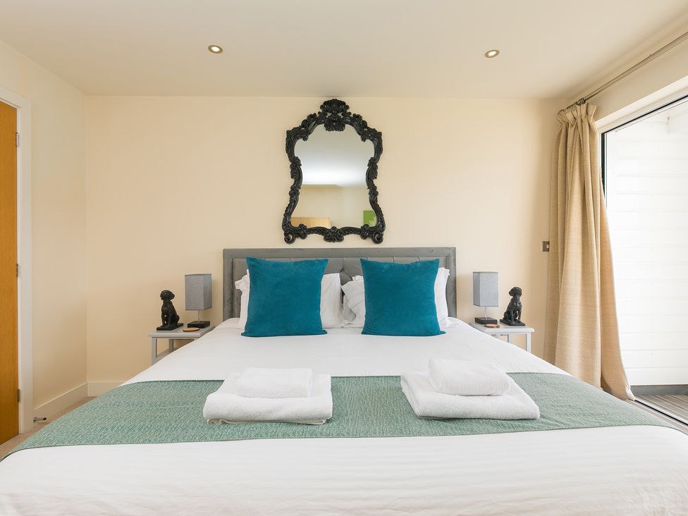 A bedroom with a bed and mirror at Whitewater Seaview in Newquay