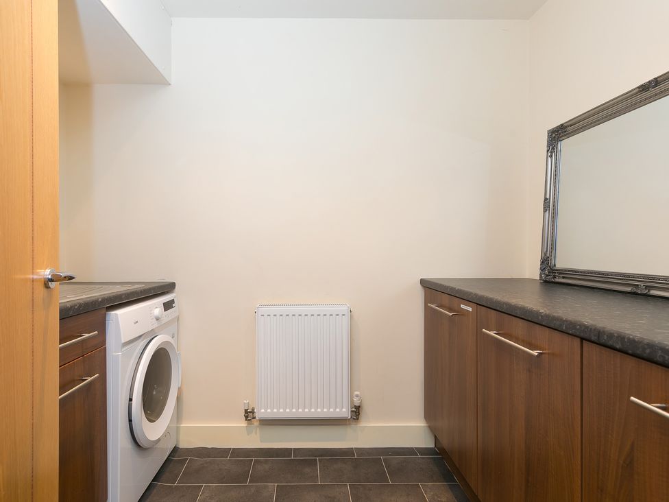 A laundry room with a washing machine and cabinets at Whitewater Seaview in Newquay