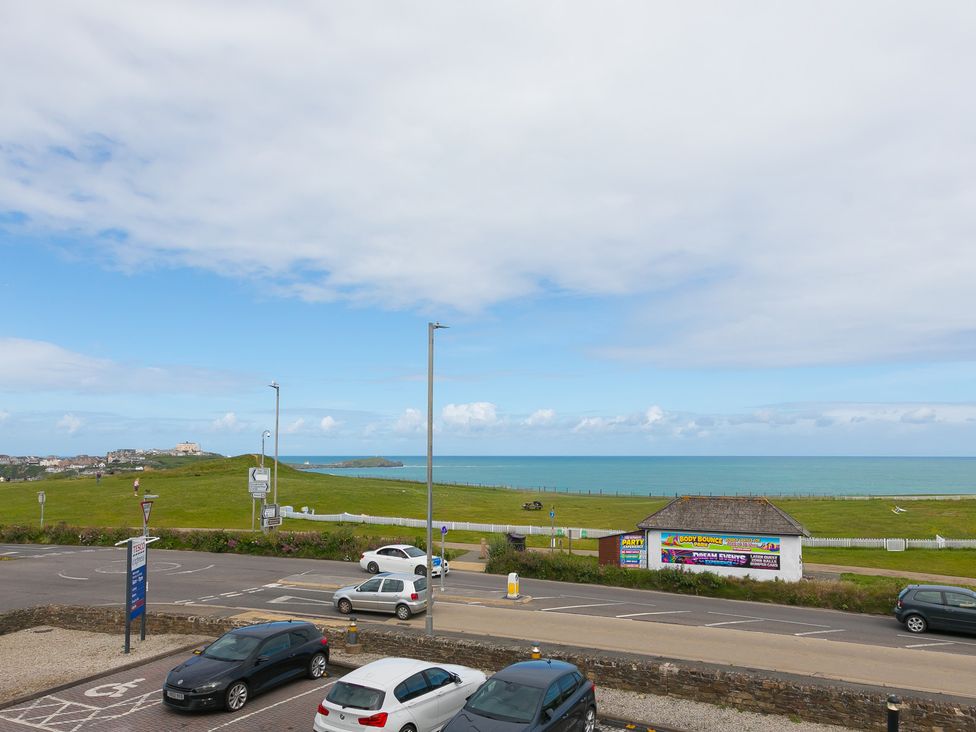 A view of the sea and grassland with parked cars at Whitewater Seaview in Newquay
