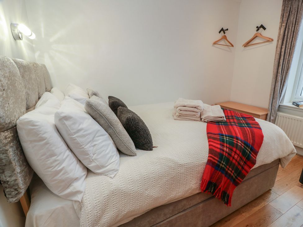 A bedroom with a bed, pillows, towels and hangers at Rosalin Cottage Dreghorn near Irvine
