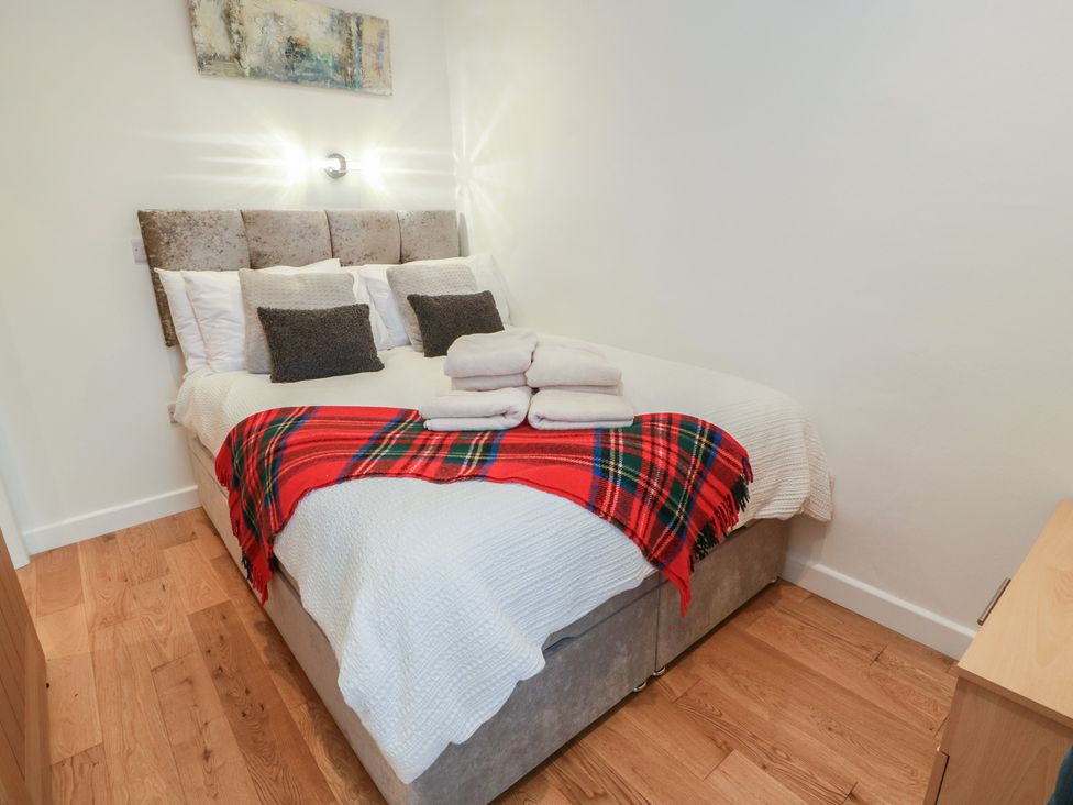 A bedroom with a bed and towels at Rosalin Cottage Dreghorn near Irvine